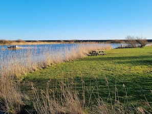 A grassy area with a picnic table and a body of water. - Charming Holiday Home in BlÃ¥vand with Hot Tub (Blavand)
