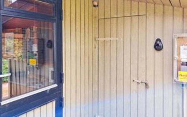 A closed door with a small window, a metal handle, and a sign on the wall. - Charming Holiday Home in BlÃ¥vand with Hot Tub (Blavand)