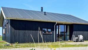 A modern building with a dark exterior, a sloped roof, and a chimney. - 8 Person Holiday Home in Ulfborg-by Traum (Ulfborg)
