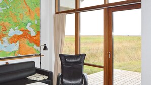 A modern room with a large window, a leather chair, a white table, and a map on the wall. - 8 Person Holiday Home in Ulfborg-by Traum (Ulfborg)
