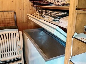 Una habitación compacta con nevera incorporada, un radiador y un estante con toallas dobladas.