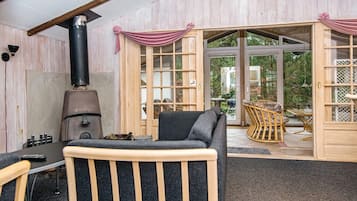 A cozy room with a fireplace, a dining area with wicker furniture, and large glass doors leading to an outdoor space.