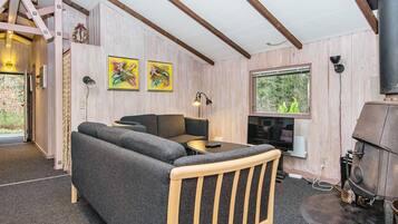 A cozy room with a sofa, a small table, a television, and a fireplace.