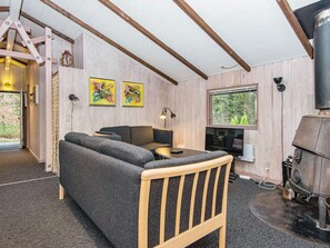 Una habitación acogedora con un sofá, una mesita, una televisión y una chimenea.
