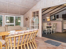 Una habitación acogedora con techo de madera, un sofá, una mesa de comedor y una zona de cocina.