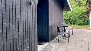 A building with a dark exterior, a door, and a small outdoor seating area with two chairs and a table. - 5 Person Holiday Home in Herning (Herning)