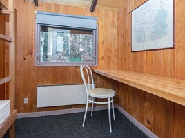 Una habitación con paredes de madera, una ventana con vistas a árboles, una silla blanca y un mapa en la pared.