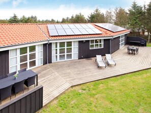 A house with a deck, solar panels, a barbecue area, and outdoor seating.