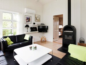 A modern living room with a black leather sofa, a white coffee table, and a black fireplace.