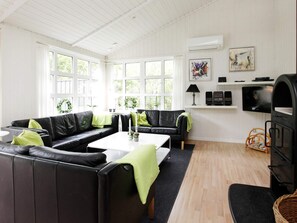 Una sala de estar moderna con un sofá de cuero negro, una mesa de centro blanca y una chimenea.