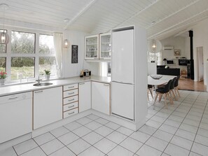 A modern kitchen with white cabinetry, a built-in refrigerator, and a dining area with a table and chairs.