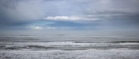 A beach with waves and a cloudy sky.