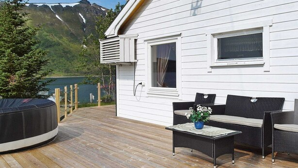 A wooden deck with outdoor furniture, a hot tub, and a mountain view. - Holiday Home in Arnøyhamn (Skjervoy)
