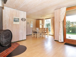 A wooden interior with a dining area, a fireplace, and a view through a glass door.
