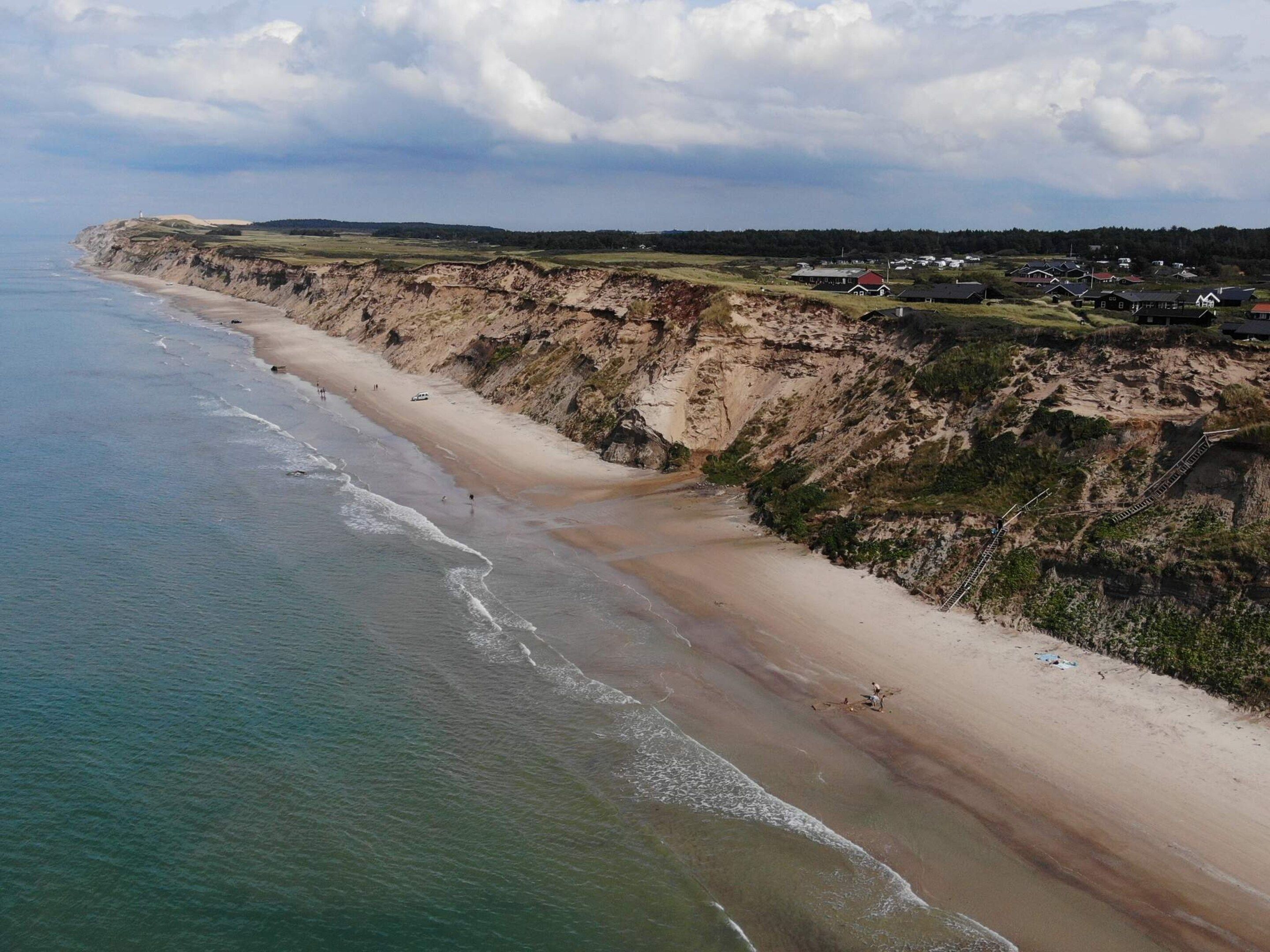 A coastal landscape with a beach, cliffs, and a small settlement.