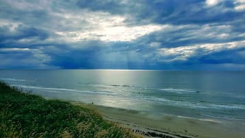 Paisagem costeira com praia e oceano sob um céu nublado.