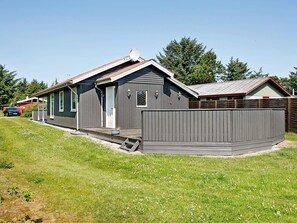 Une maison à deux étages avec un porche couvert et une cour clôturée.