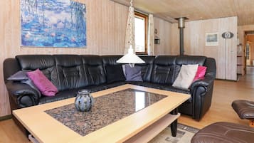 Uma sala de estar moderna com um sofá de couro preto, uma mesa de centro de madeira e um quadro na parede.