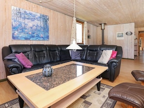 A modern living room with a black leather sofa, a wooden coffee table, and a painting on the wall. - 6 Person Holiday Home in Lokken (Lokken)
