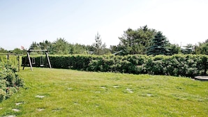 A grassy outdoor area with a wooden swing set and a hedge. - 6 Person Holiday Home in Lokken-by Traum (Lokken)
