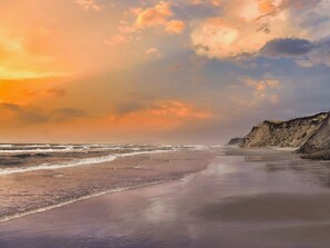 A beach with waves, a cliff, and a sunset. - 6 Person Holiday Home in Lokken (Lokken)
