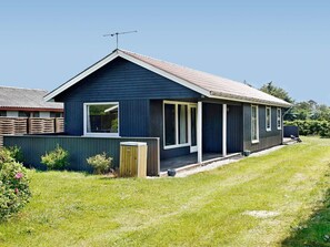 A single-story house with a dark exterior, a sloped roof, and a visible antenna.