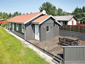 A two-story house with a wooden deck, a small patio, and a fenced backyard.