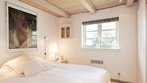 A bedroom with a bed, a window with blinds, a lamp, and a painting on the wall. - 5 Person Holiday Home in Vejby-by Traum (Vejby)