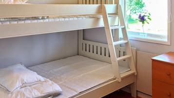 A bunk bed with a ladder, a pillow, and a small wooden dresser in a room with a window.