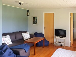A living room with a sofa, a coffee table, a television on a stand, and a door leading to another room. - Holiday Home in Ljungskile (Ljungskile)