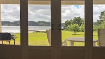 A view through a door of a grassy area with a body of water, a dock, and a boat.