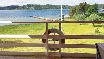 Eine Holzterrasse mit einem Rettungsboje und einem Schild, mit Blick auf einen See mit einem Steg und einem kleinen Gebäude.