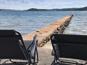 Two black metal chairs facing a concrete pier extending into a body of water with a distant shoreline. - Holiday Home in Ljungskile (Ljungskile)