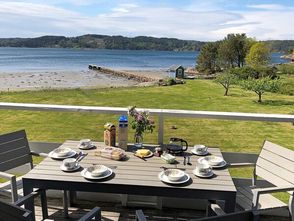 A table set for dining with a view of a lake and a small house in the distance. - Holiday Home in Ljungskile (Ljungskile)
