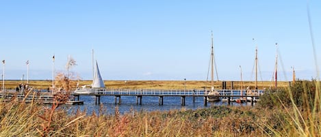A pier extending into a body of water with boats and a sailboat docked.