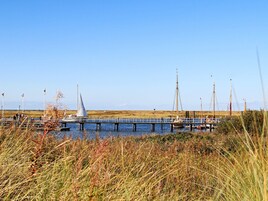 Un muelle que se adentra en un cuerpo de agua con barcos y un velero.