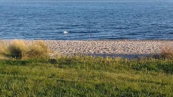 Een kustlandschap met een kiezelstrand en een gazon op de voorgrond.