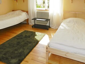 A room with two single beds, a radiator, a small table, and a green rug on a wooden floor. - 3 Person Holiday Home in Lysekil (Lysekil)