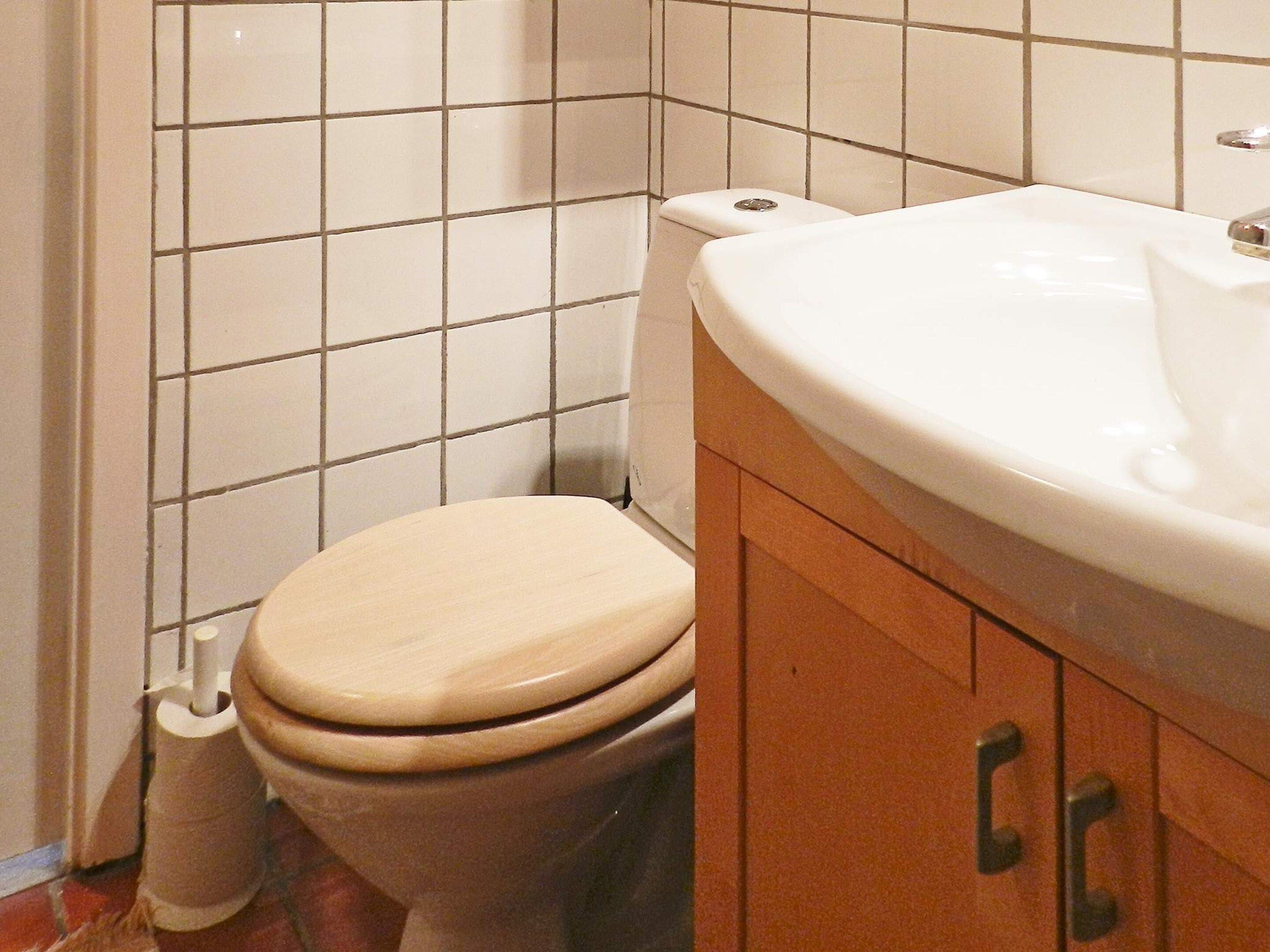Une salle de bain avec des toilettes, un lavabo et des murs carrelés.