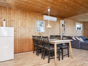A wooden-paneled room with a dining table, chairs, a sofa, and a white refrigerator. - 6 Person Holiday Home in Ebeltoft-by Traum (Ebeltoft)