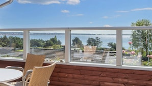 Un balcone con vista su un lago, sedie in vimini, un tavolo e un muro in legno.
