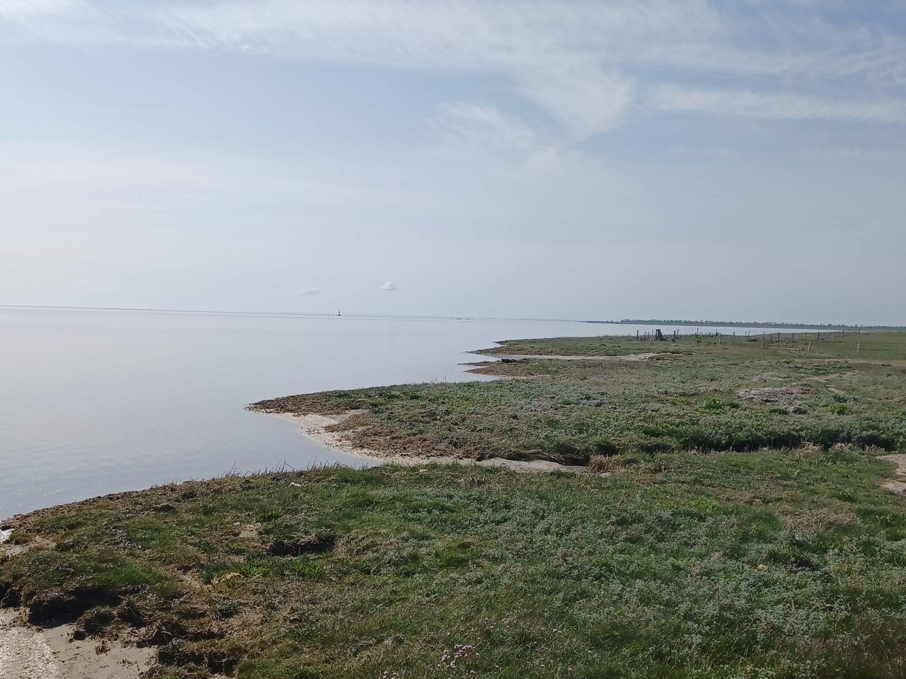 A coastal landscape with a sandy beach and grassy areas.