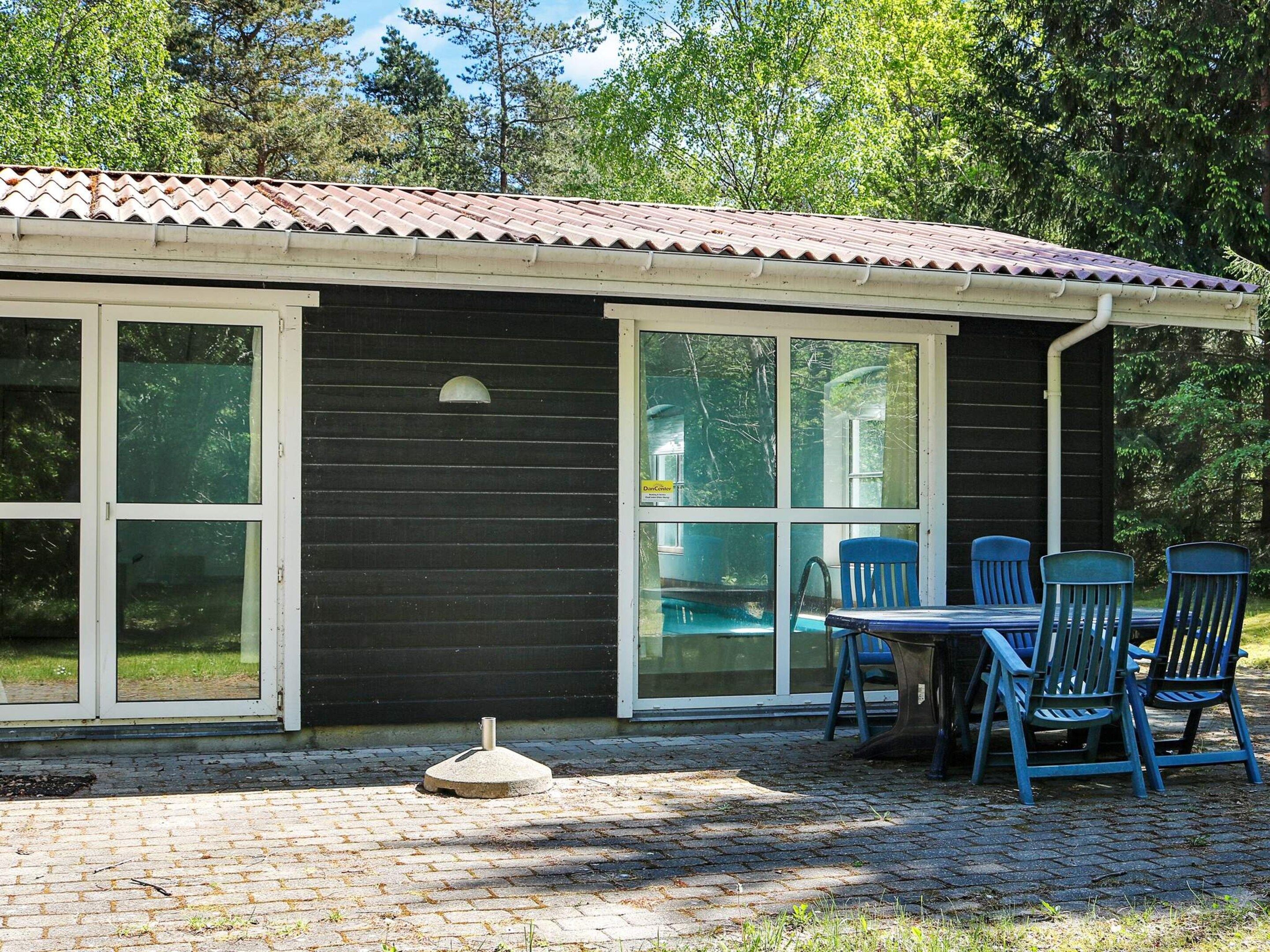 A building with a tiled roof, large windows, and a brick patio with outdoor seating.