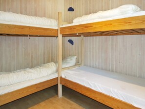 Ein Schlafraum mit Etagenbetten, Holzrahmen und weißer Bettwäsche.