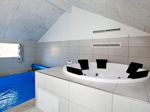 A modern bathroom with a freestanding bathtub, a built-in shower, and a window providing natural light.