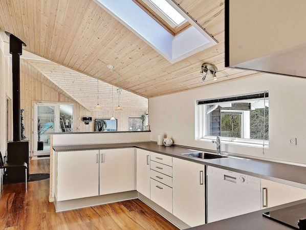 A modern kitchen with a skylight, wooden ceiling, and a view of the outdoors. - 5 Star Holiday Home in Hornbaek (Hornbaek)