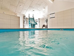 An indoor swimming pool with a slide, tiled walls, and ceiling lights. - 5 Star Holiday Home in Hornbaek (Hornbaek)