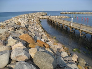 A rocky shoreline with a wooden pier extending into calm waters.