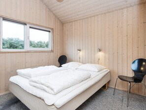 A bedroom with a bed, two bedside lamps, a chair, and a window.