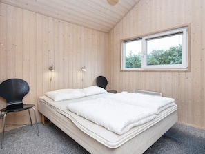 A room with a bed, a chair, a window, and wall-mounted lights.